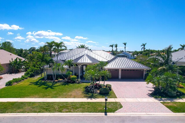 15730 Cedar Grove Ln, Wellington, FL 33414 - view of front of home featuring a standing seam roof, an attached garage, metal roof, decorative driveway, and a front lawn
