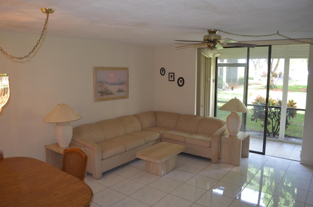 living area featuring light tile patterned flooring, ceiling fan, and a textured ceiling