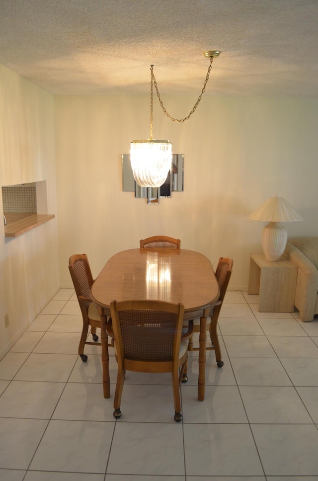 dining space with light tile patterned flooring, a notable chandelier, and a textured ceiling