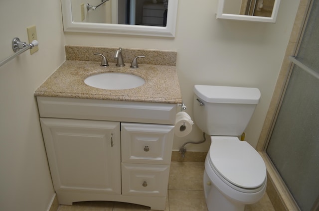 bathroom featuring tile patterned flooring, vanity, toilet, and an enclosed shower