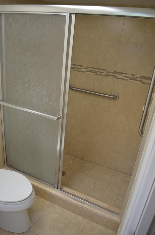 full bathroom with a stall shower, toilet, and tile patterned floors