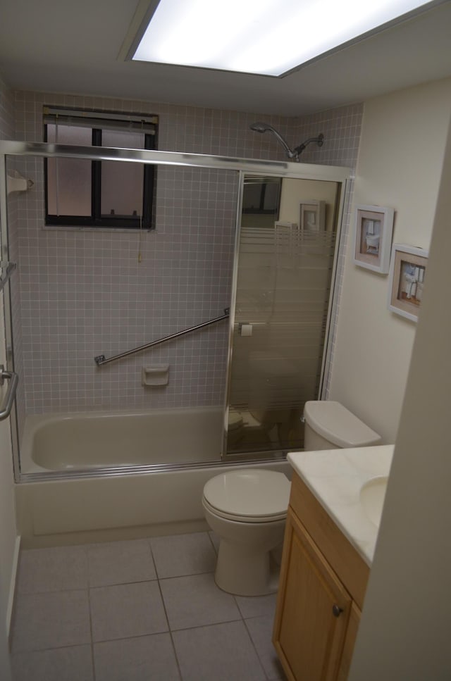 bathroom featuring toilet, tile patterned flooring, combined bath / shower with glass door, and vanity