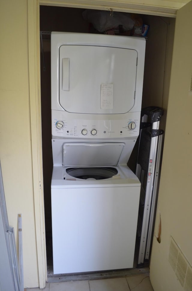 laundry room featuring laundry area, stacked washer / dryer, light tile patterned flooring, and visible vents