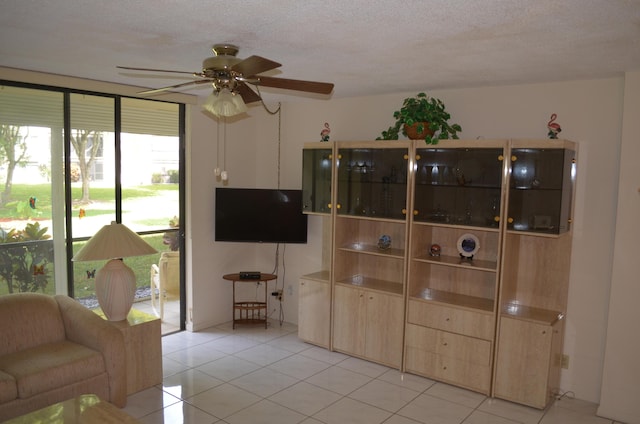 living area with light tile patterned floors, a ceiling fan, and a textured ceiling