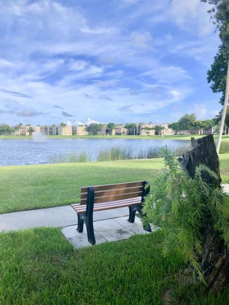 surrounding community with a water view and a lawn