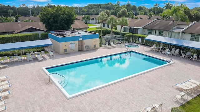 community pool featuring a residential view, a patio area, and a hot tub