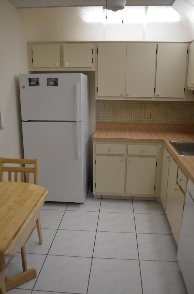 kitchen featuring decorative backsplash, freestanding refrigerator, light countertops, and cream cabinets