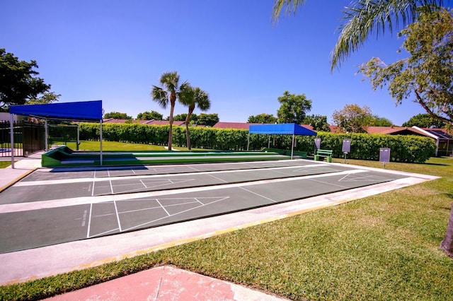 view of community with fence, shuffleboard, and a yard