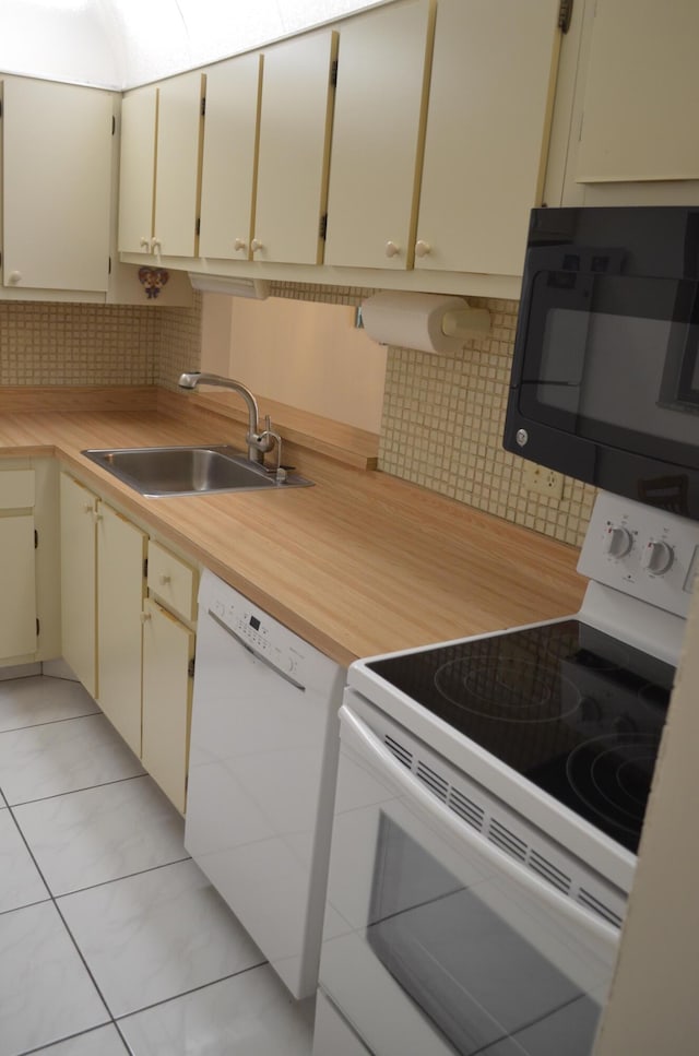 kitchen with light countertops, white appliances, backsplash, and a sink