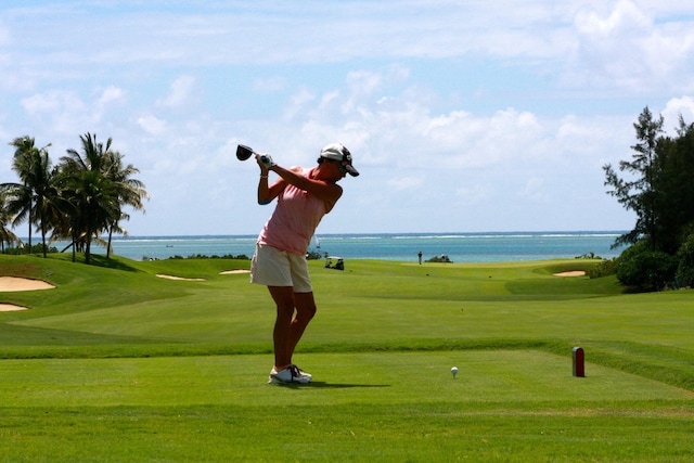 view of property's community with view of golf course, a yard, and a water view