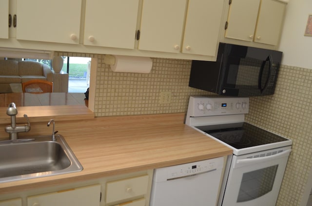 kitchen featuring white appliances, butcher block counters, backsplash, and a sink