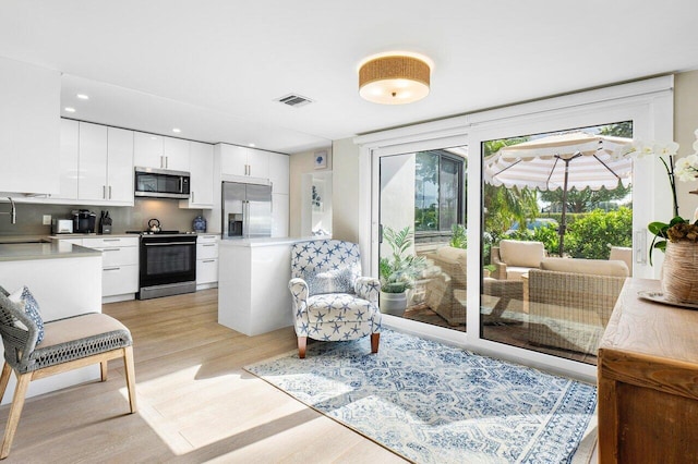 kitchen with appliances with stainless steel finishes, white cabinets, light countertops, and light wood finished floors