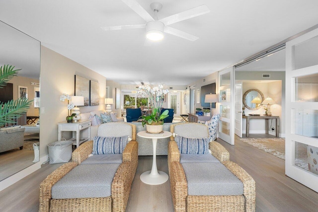 living area featuring a ceiling fan, visible vents, and wood finished floors