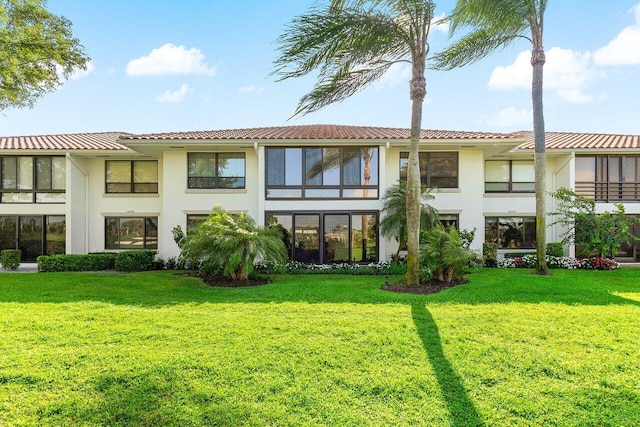 back of property with a lawn, a tiled roof, and stucco siding