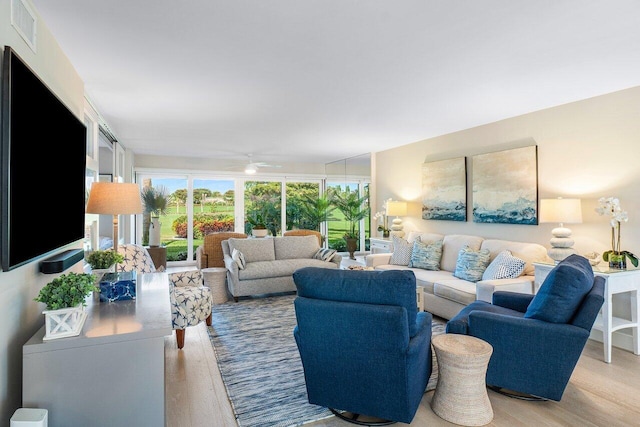 living room with a ceiling fan, visible vents, and light wood finished floors