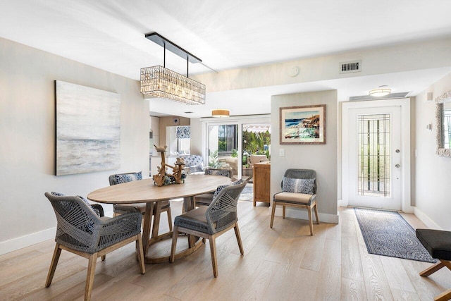 dining room featuring light wood finished floors, baseboards, and visible vents