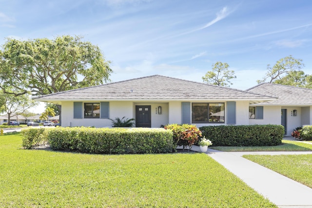 single story home with a tiled roof, a front lawn, and stucco siding