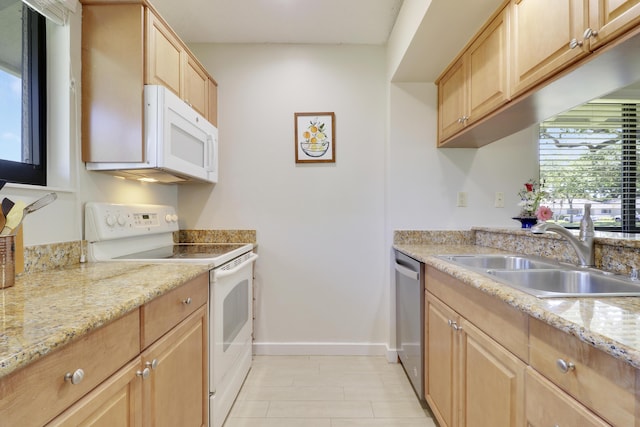 kitchen with light brown cabinets, white appliances, a sink, and baseboards