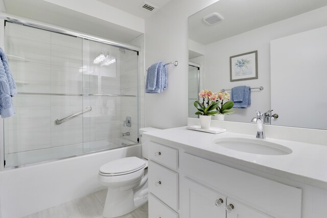 bathroom with toilet, visible vents, combined bath / shower with glass door, and vanity