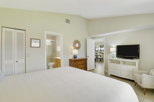 bedroom featuring lofted ceiling, connected bathroom, visible vents, and a closet