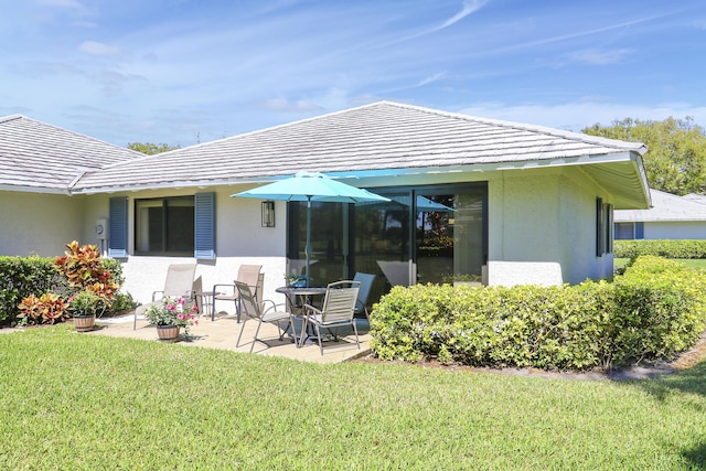 back of property with a patio area, a lawn, and stucco siding