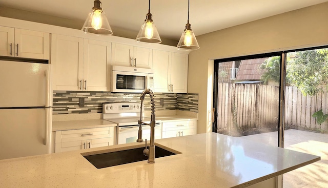 kitchen featuring white appliances, tasteful backsplash, light stone counters, decorative light fixtures, and white cabinetry