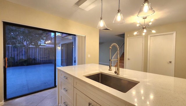 kitchen with visible vents, white cabinets, decorative light fixtures, light stone countertops, and a sink