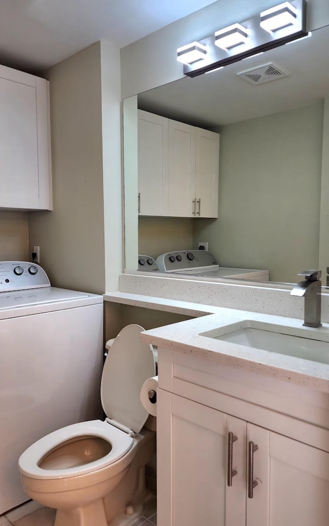 half bath featuring toilet, vanity, visible vents, and independent washer and dryer