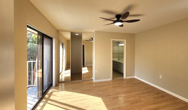 unfurnished bedroom with a sink, access to exterior, baseboards, light wood-type flooring, and ensuite bath