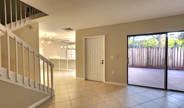 foyer with light tile patterned floors, visible vents, baseboards, stairway, and a notable chandelier