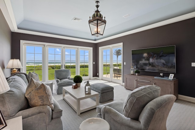 carpeted living area featuring an inviting chandelier, a raised ceiling, visible vents, and baseboards