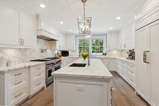 kitchen featuring range with two ovens, a center island, white cabinets, a sink, and premium range hood