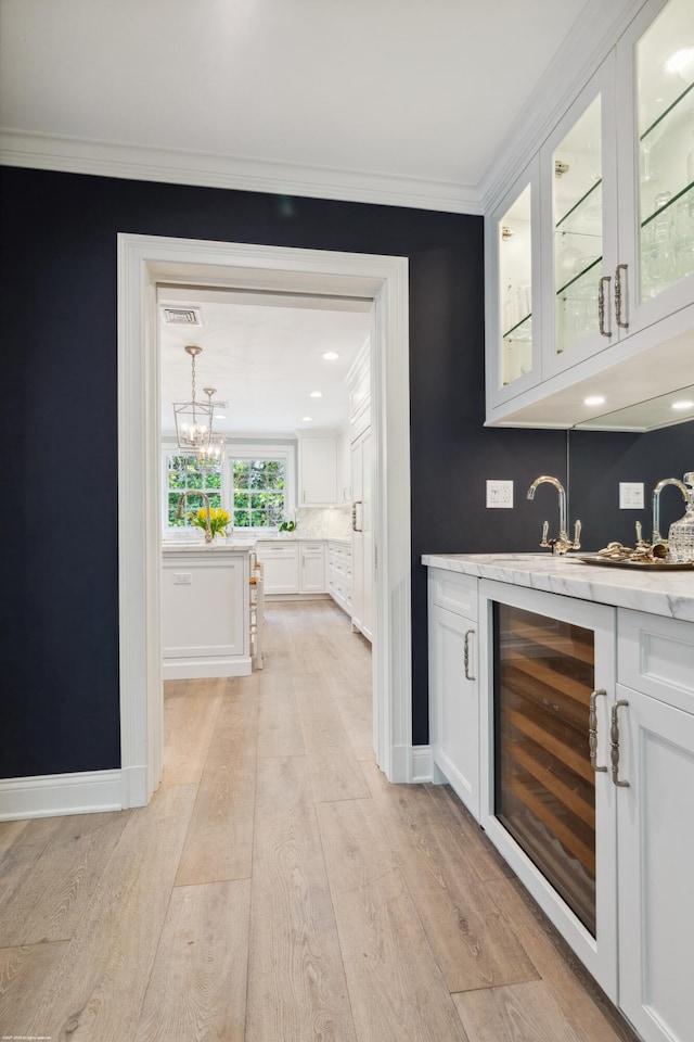 bar featuring visible vents, wine cooler, crown molding, light wood-style floors, and indoor wet bar