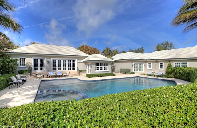 view of pool featuring entry steps, a patio, french doors, and a pool with connected hot tub