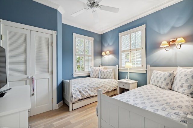 bedroom featuring light wood-type flooring, ceiling fan, ornamental molding, and a closet