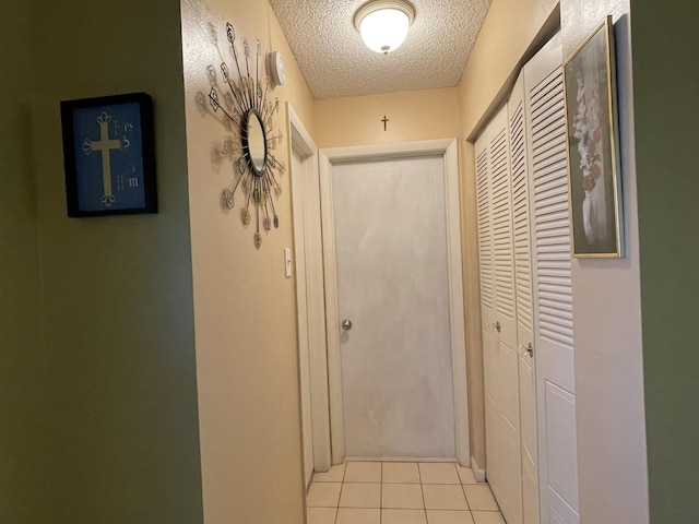 corridor featuring light tile patterned floors and a textured ceiling