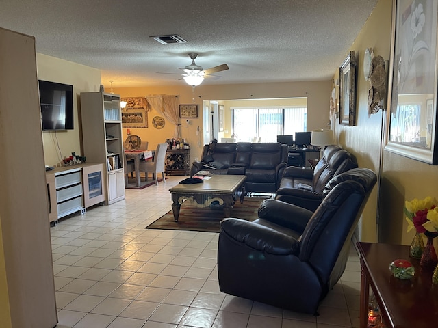 living room with a textured ceiling, ceiling fan, light tile patterned floors, and visible vents