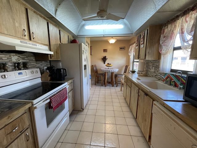 kitchen with white appliances, vaulted ceiling, under cabinet range hood, a sink, and light tile patterned flooring