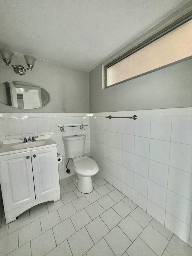 bathroom with toilet, tile patterned floors, tile walls, and vanity