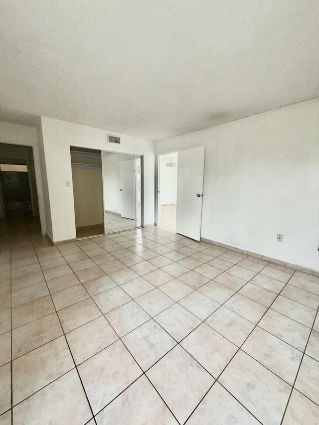 spare room featuring light tile patterned floors, visible vents, and a textured ceiling