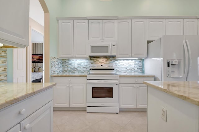 kitchen with white appliances, light tile patterned flooring, light stone countertops, and white cabinets