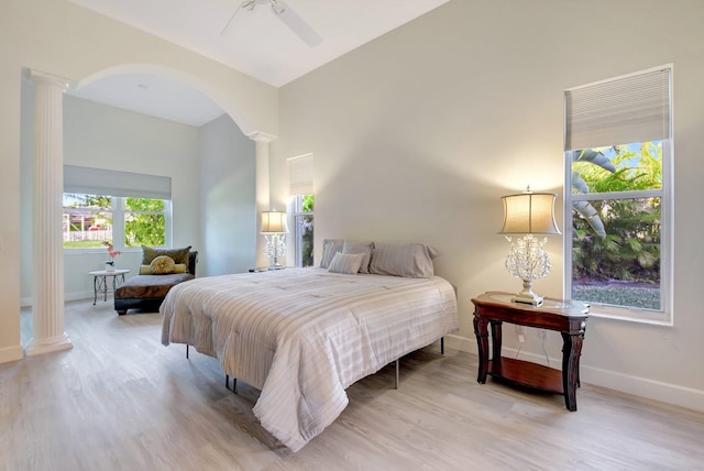 bedroom featuring decorative columns, baseboards, and wood finished floors