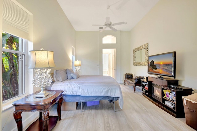 bedroom with a high ceiling, wood finished floors, and a ceiling fan