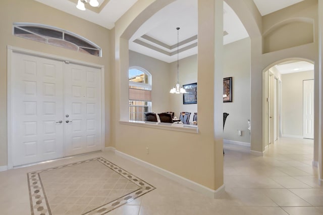 9429 Lantern Bay Cir, West Palm Beach, FL 33411 - tiled foyer with arched walkways, a chandelier, baseboards, and a towering ceiling