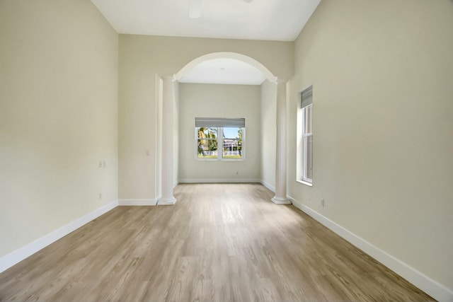 9429 Lantern Bay Cir, West Palm Beach, FL 33411 - spare room with ornate columns, arched walkways, light wood-style floors, and baseboards
