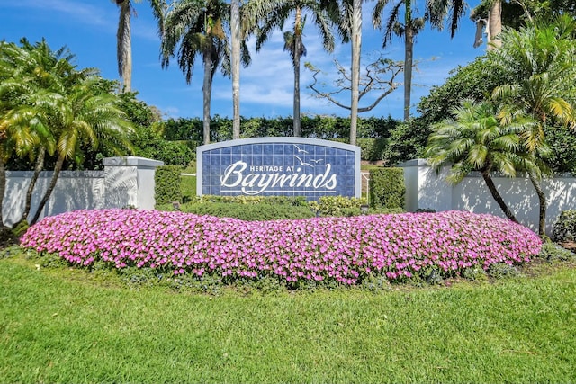 community / neighborhood sign with a lawn and fence