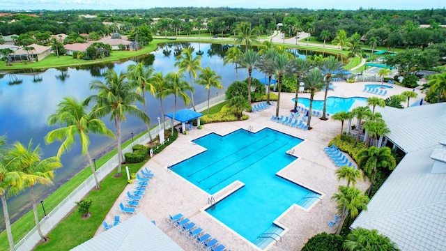 pool featuring a patio, a water view, and fence