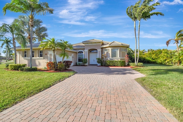 mediterranean / spanish-style house featuring an attached garage, stucco siding, decorative driveway, and a front yard