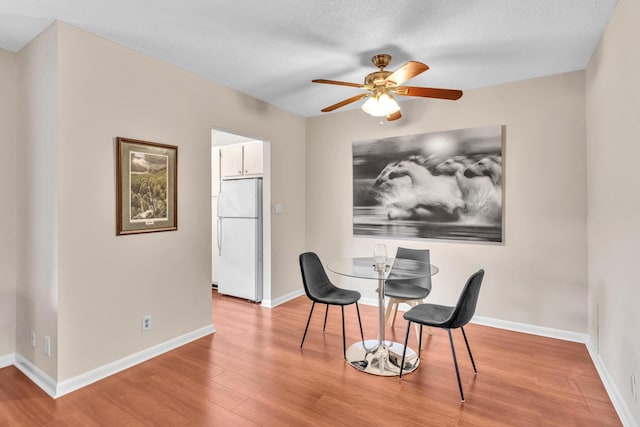 dining area featuring baseboards, wood finished floors, and a ceiling fan