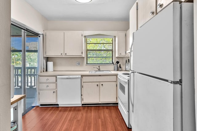 kitchen featuring a sink, white appliances, wood finished floors, and light countertops